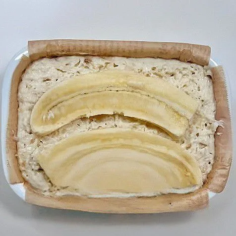 Setelah mengembang, letakkan 1 buah pisang utuh di atas adonan, lalu panggang ke dalam air fryer pada suhu 160°C selama 35 menit.