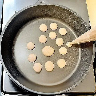 Panaskan wajan anti lengket dengan menggunakan api kecil. Masukkan adonan ke piping bag, lalu tuangkan adonan berbentuk bulat-bulat kecil.