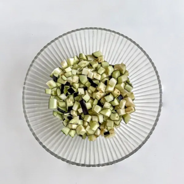 Potong terong menjadi dadu kecil. Rendam dengan sedikit air hangat lalu tiriskan.