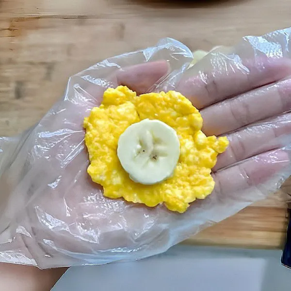 Oleskan minyak pada telapak tangan. Ambil 25 gr adonan tepung beras, pipihkan. Letakkan irisan pisang di tengah adonan, tutup dengan adonan lagi. Bentuk menjadi bulatan pipih kecil.