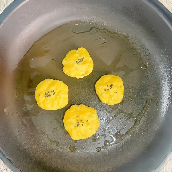 Panaskan wajan anti lengket, oleskan tipis dengan minyak. Masukkan bulatan adonan yang sudah dibentuk. Taburi dengan sedikit biji wijen hitam di atasnya.