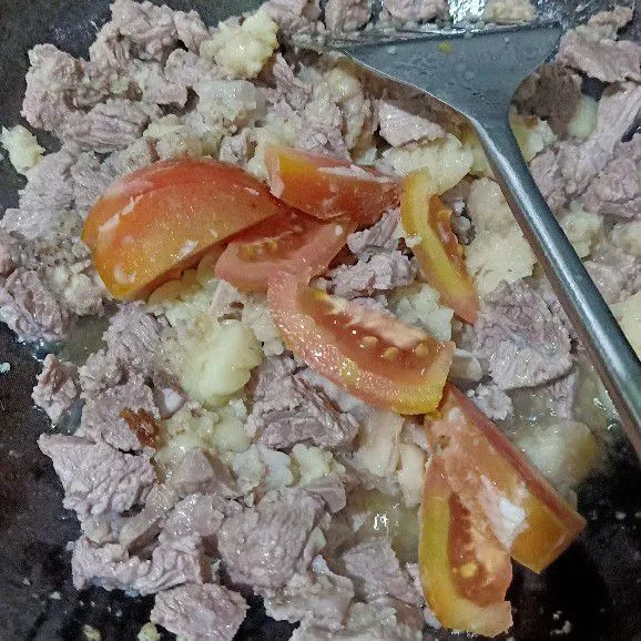 Masukkan daging sapi sedikit kedalam wajan biar tercampur dengan lemak. Masukkan irisan tomat kedalam wajan, lalu oseng bersamaan.