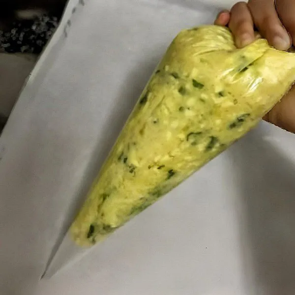 Masukkan adonan ke dalam plastik segitiga. Semprotkan adonan di atas loyang dengan bentuk stik memanjang.