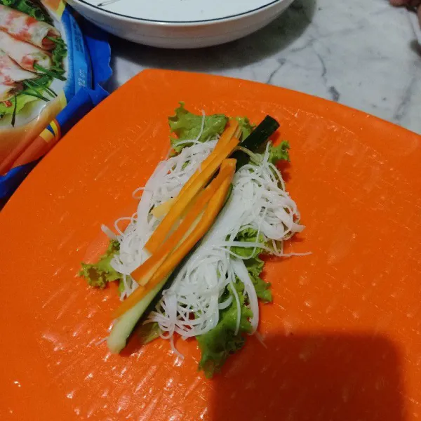 Taruh bihun dan potongan wortel yang memanjang diatas selada bokor.