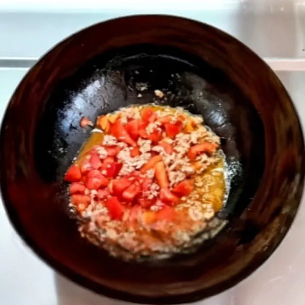Masukkan tomat, lanjut tumis hingga hancur dan berair.