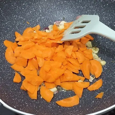 Tambahkan irisan halus wortel, aduk hingga layu. Tuang air. Masak hingga wortel empuk.