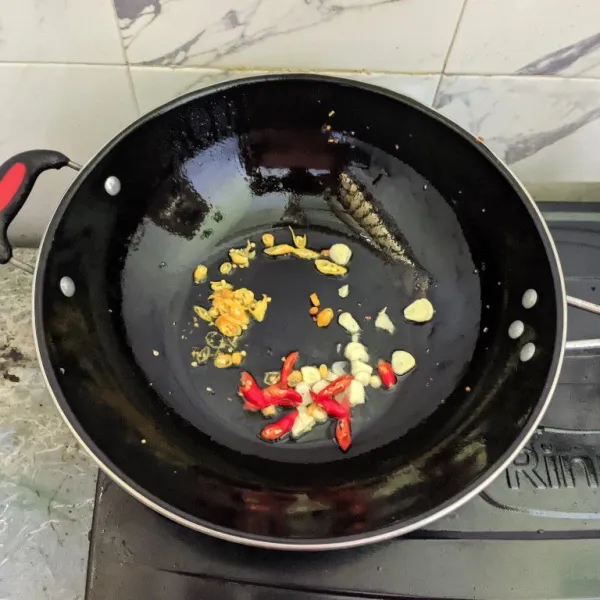 Tumis bawang putih, cabai rawit, dan cabai keriting merah hingga harum dan sedikit layu.