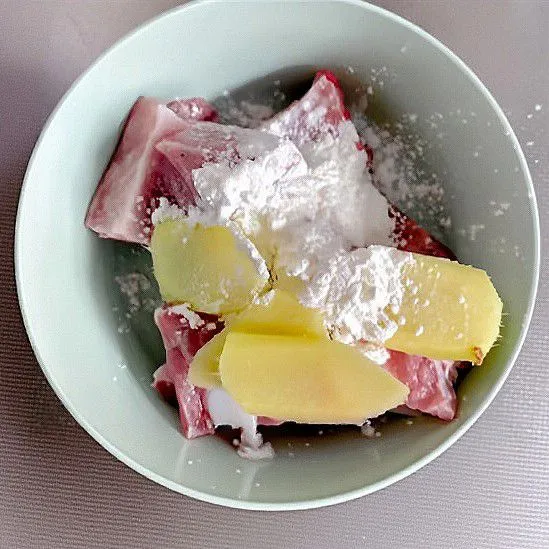 Masukkan iga ke dalam mangkuk, lalu tambahkan jahe iris, tepung maizena, dan minyak sayur. Aduk rata.