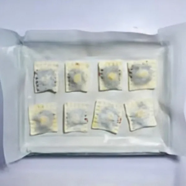 Lipat kulit menjadi bentuk persegi, tekan sisi-sisinya dengan garpu agar tertutup rapat. Oles kembali bagian atas dengan sisa telur kocok