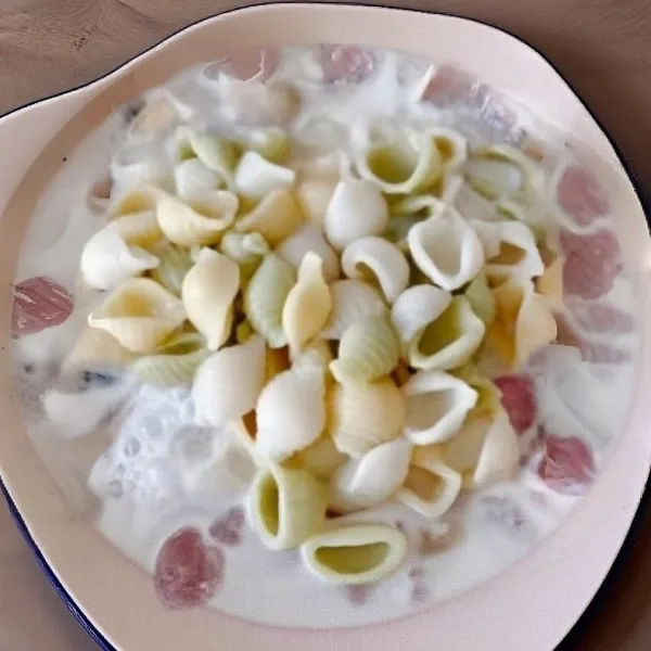 Masukkan pasta yang telah direbus, aduk rata agar semua bahan terlapisi saus krim. Bumbui dengan garam dan lada hitam sesuai selera