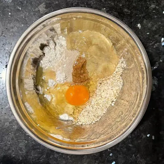 Dalam mangkuk, masukkan 80 gr tepung terigu protein rendah, 30 gr gandum oat, 3 gr ragi instan, dan aduk rata. Tambahkan 1 butir telur, aduk lagi