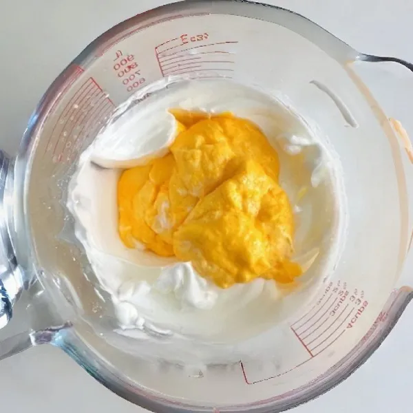 Setelah rata, tuang kembali campuran ini ke sisa putih telur dan aduk sampai lembut dan rata. Masukkan tepung terigu dan susu bubuk. Aduk rata. Tuang adonan ke dalam piping bag