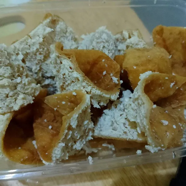 Potong tahu diagonal menjadi segitiga. Balik tahu, bagian dalam berada di luar. Ambil isian tahu berwarna putih, sisihkan untuk dicampur ke dalam adonan.