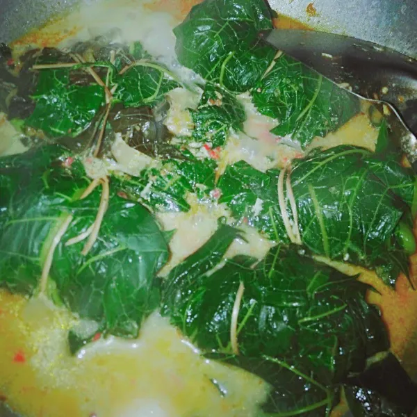 Masukkan buntil daun pepaya, lalu masak hingga matang dan bumbu meresap.