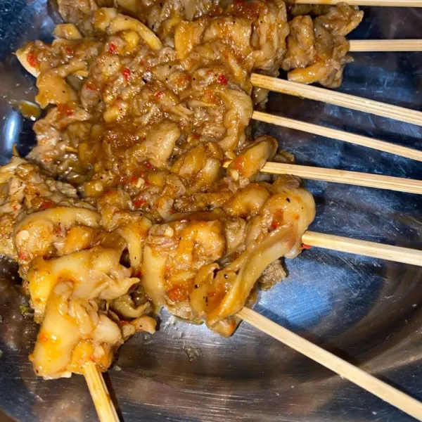 Tusuk jamur yang sudah ditumis menggunakan tusuk sate.