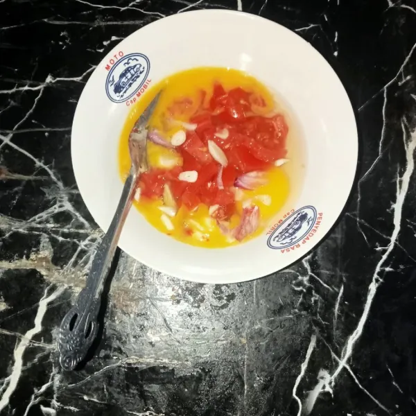 Masukkan irisan bawang merah,bawang putih,daun bawang,tomat, dan cabe merah giling ke dalam wadah telur