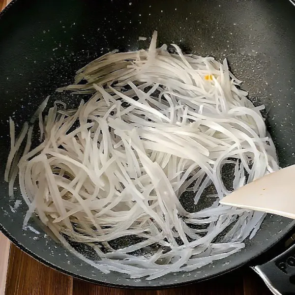 Masukkan 150 gr lobak putih serut ke dalam wajan. Tumis selama ±2 menit hingga agak layu dan harum