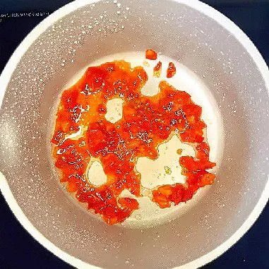 Tuang minyak sayur ke dalam wajan dalam keadaan dingin, masukkan tomat cincang, dan tumis hingga lembek serta keluar airnya