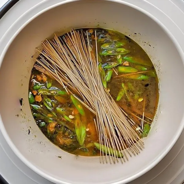 Tuangkan 400 ml air mendidih ke dalam wajan, aduk rata. Masukkan 150 gr mie soba