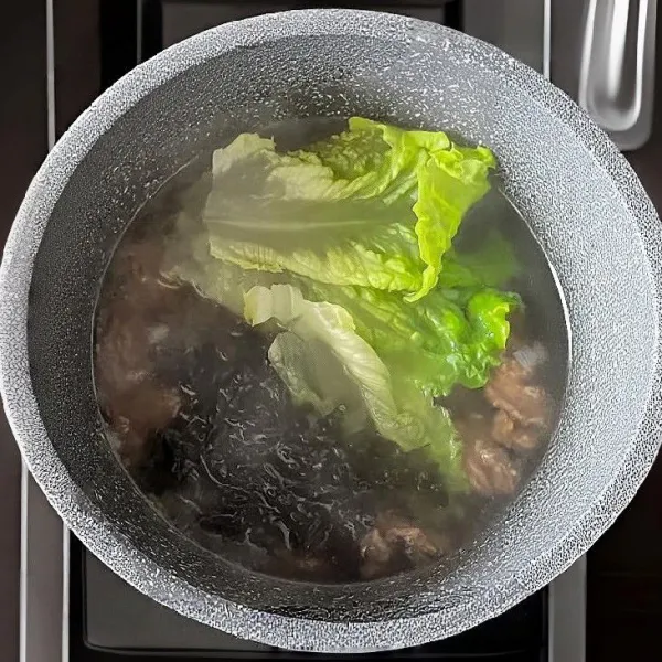 Masukkan rumput laut kering dan daun selada. Masak kembali hingga sayuran layu dan rumput laut mengembang.