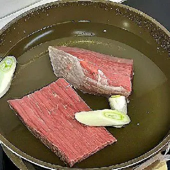 Masukkan daging sapi ke dalam panci berisi air dingin. Tambahkan daun bawang dan arak masak, lalu rebus selama 10 menit.