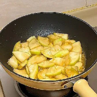 Masukkan madu, lalu aduk hingga rata. Tuangkan air dan kecilkan api. Masak hingga terong empuk.