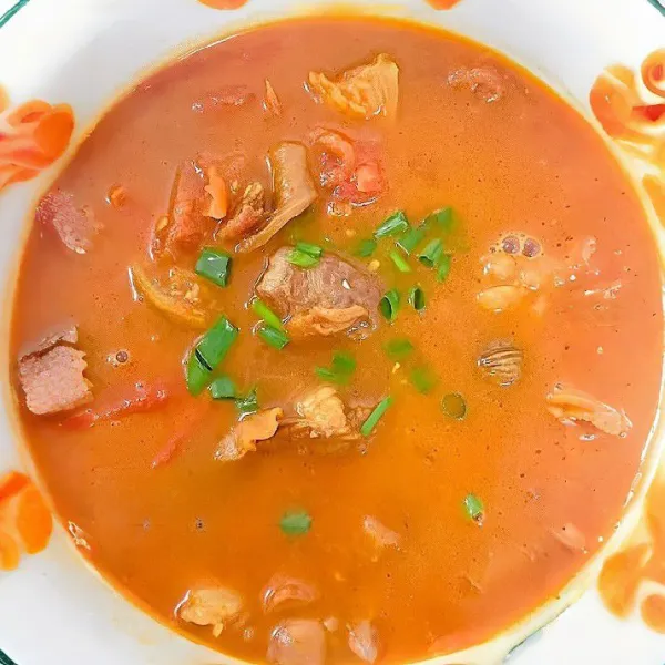 Tambahkan tomat potong besar, lanjutkan memasak selama 10 menit hingga tomat melunak dan kuah menjadi kental. Taburi daun bawang cincang di atasnya.