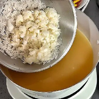 Masukkan beras putih dan pasta ubi ke dalam kaldu udang. Setelah mendidih, kecilkan api dan masak selama 10 menit hingga beras mulai mengembang dan lembut.