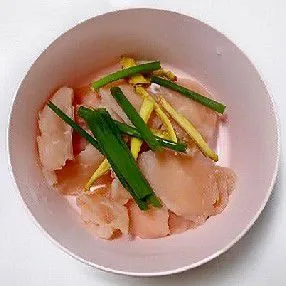 Masukkan dada ayam iris ke dalam mangkuk, lalu tambahkan jahe iris dan daun bawang iris.