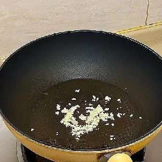 Panaskan minyak goreng dalam wajan, lalu tumis bawang putih cincang hingga harum.