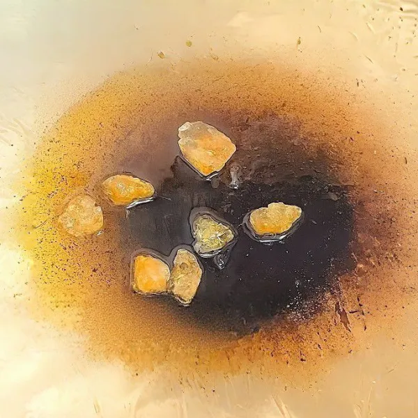 Panaskan minyak goreng di wajan. Setelah minyak panas, tambahkan gula batu dan biarkan meleleh hingga berbusa dan berubah warna menjadi cokelat keemasan.