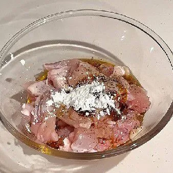 Masukkan potongan daging paha ayam ke dalam mangkuk, tambahkan arak masak, kecap asin, saus tiram, lada bubuk, dan tepung maizena. Aduk rata dan diamkan selama 20 menit agar bumbu meresap.