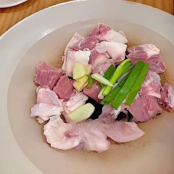 Masukkan daging sapi brisket ke dalam panci berisi air dingin, tambahkan jahe, daun bawang, dan arak masak. Rebus hingga air mendidih. Angkat dan tiriskan, lalu bilas dengan air bersih,