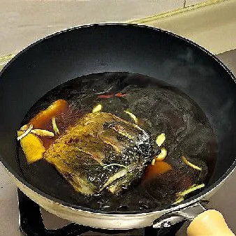 Tuangkan kecap asin, kecap manis, arak masak, gula pasir, dan air panas hingga menutupi setengah bagian ikan.