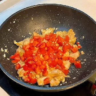 Masukkan tomat berbentuk dadu, lalu aduk sampai rata. Tumis semua bahan hingga agak layu, lalu masak selama 3 menit agar bumbu meresap.