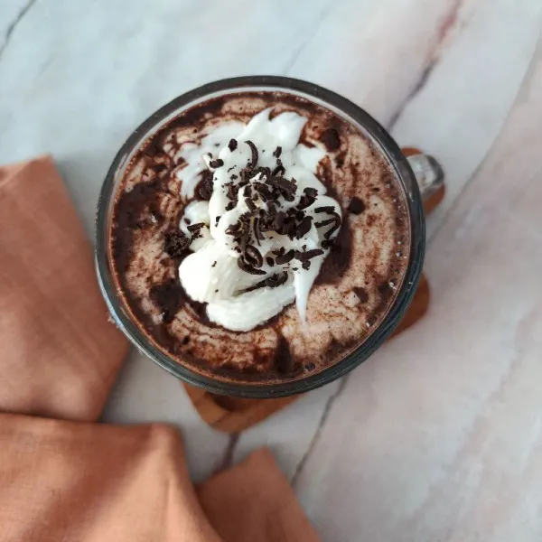 Tambahkan whipped cream kocok dan taburan cokelat batang serut. Sajikan selagi panas.