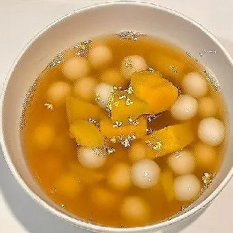 Setelah semua bola ketan mengapung. Tambahkan 1 sdm kental manis. Taburkan bunga osmanthus kering di atasnya