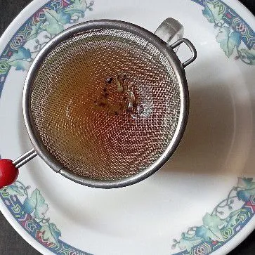 Tuang air rebusan jahe dan gula dengan cara disaring.