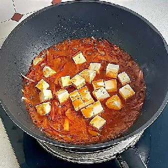 Tambahkan tahu dan kue beras, lalu tuang lagi sekitar 100 ml air bersih. Masak hingga kuah mulai mengental