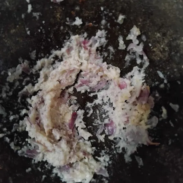 Haluskan bawang merah, bawang putih, kemiri, dan lengkuas muda menggunakan ulekan.