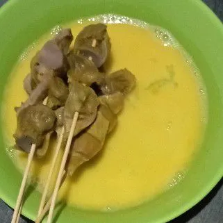 Kocok adonan pembalur, lalu gulingkan sate ampela hingga terbalur merata.