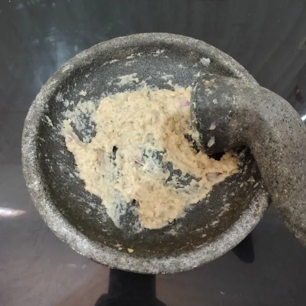 Haluskan bawang merah, bawang putih, kemiri, dan merica menggunakan ulekan.