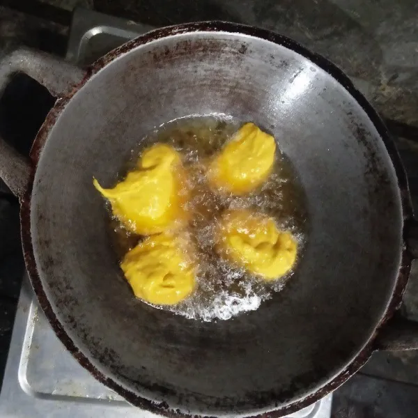 Panaskan minyak goreng dengan api sedang, lalu goreng adonan cekodok labu kuning hingga berubah warna menjadi kuning kecokelatan.