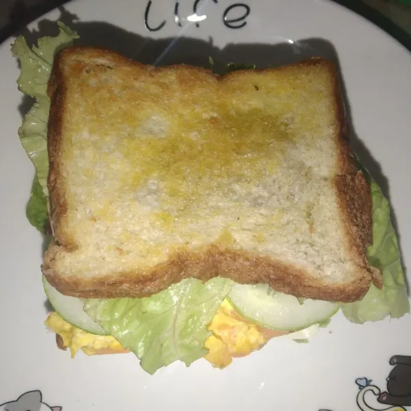 Tata kembali dengan roti yang diolesi saus, telur, timun, selada, dan roti tawar.