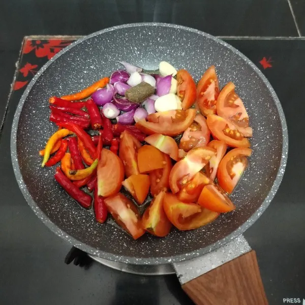 Panaskan minyak di wajan, lalu masukkan cabai keriting, cabai rawit, bawang merah, bawang putih, terasi, dan tomat, goreng hingga layu.