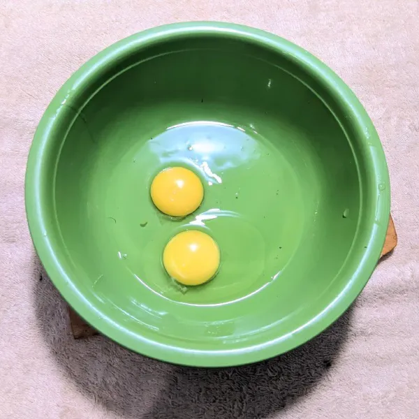 Pecahkan 2 butir telur ke dalam wadah.