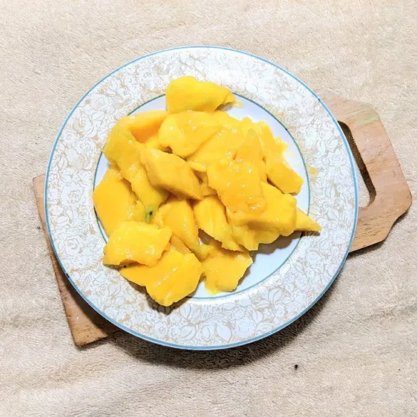 Kupas buah mangga, lalu iris sesuai selera.