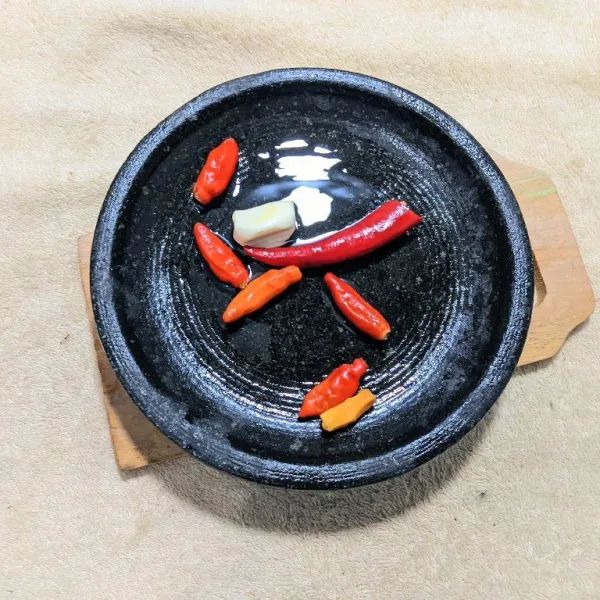 Haluskan cabe merah besar, cabe rawit, bawang putih, dan kunyit menggunakan cobek hingga lembut.