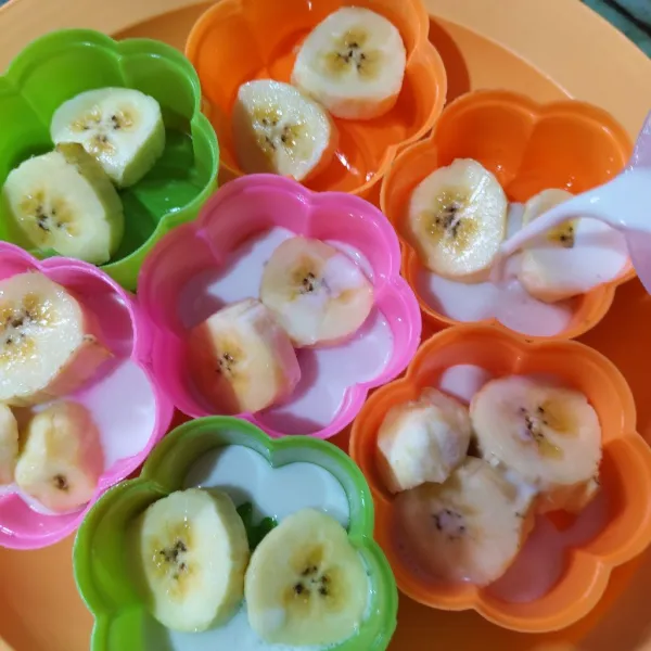 Oles cetakan dengan minyak goreng. Masukkan irisan pisang, tuang adonan putih ⅓ bagian