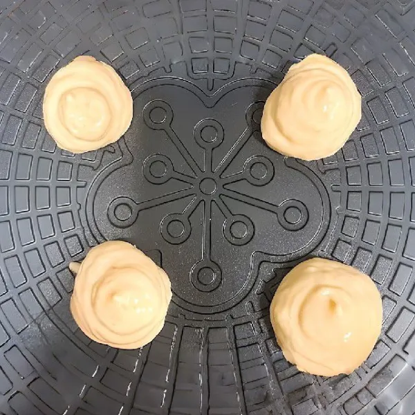 Tuang adonan ke dalam piping bag. Panaskan cetakan, tekan adonan keluar perlahan ke atas cetakan